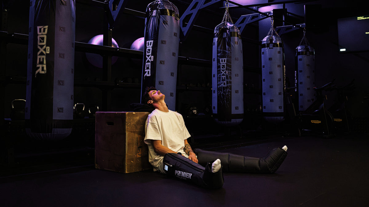Resting in AeroBoots Pro against a box at the gym, legs out in front